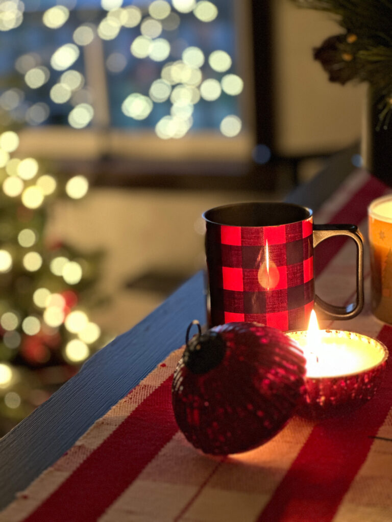 A CHristmas table with tea and candles with a Christmas tree in the background- Finding Peace During the Holidays